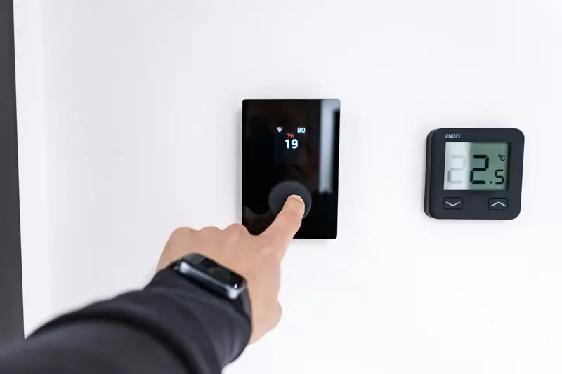 Mano ajustando un panel de control digital en la pared